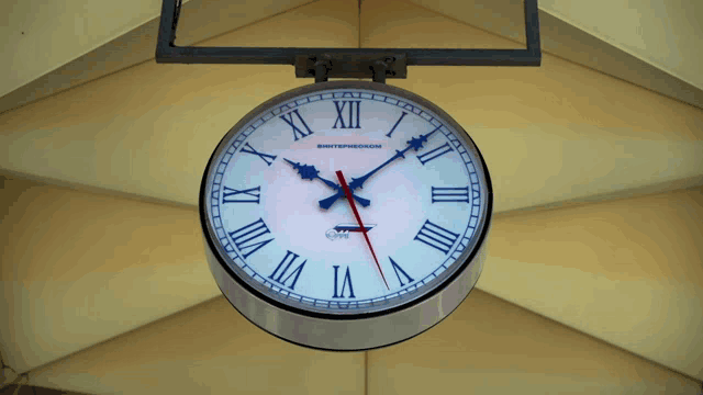 a white clock with roman numerals shows the time as almost 5:00