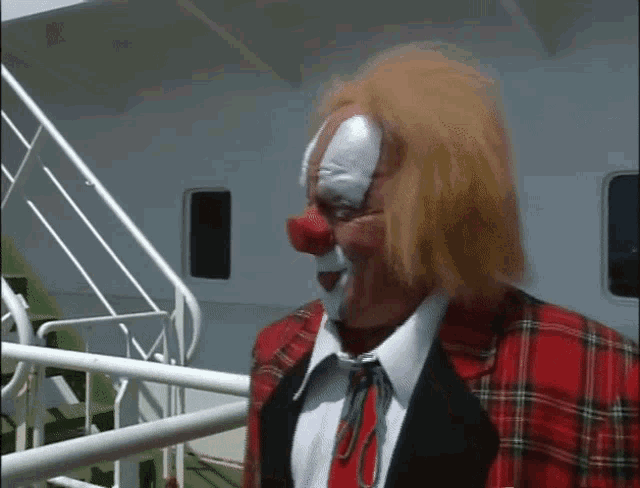a man dressed as a clown is standing in front of stairs