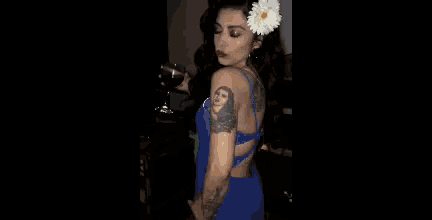 a woman wearing a flower in her hair is holding a glass of wine .