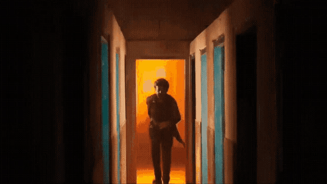 a man is walking down a hallway holding a machete .