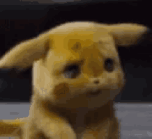 a close up of a stuffed animal sitting on a table with a sad look on its face .