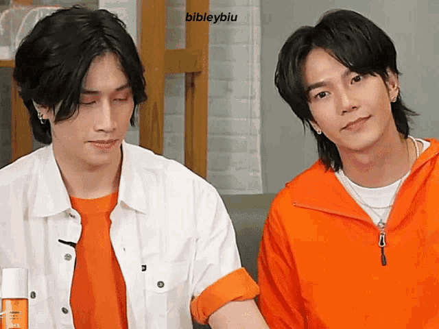 two young men are sitting next to each other and one of them is wearing a white shirt