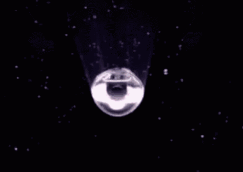 a purple light is shining on a pink object in the middle of space .