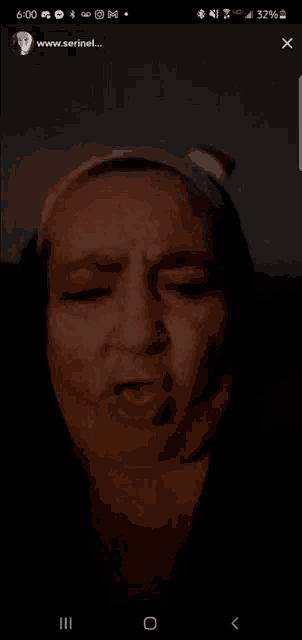 a woman 's face is shown on a cell phone screen with the website www.serinet.com visible
