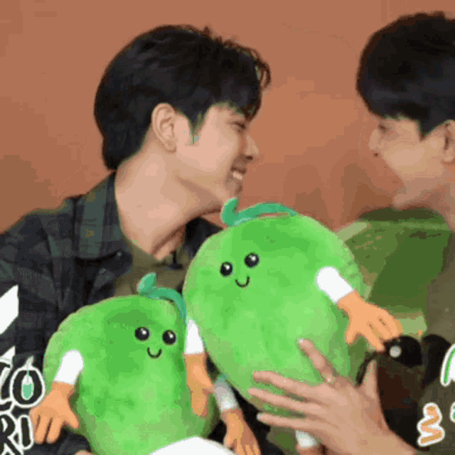two men are holding green stuffed animals and one of them is wearing a shirt that says ' i love you ' on it