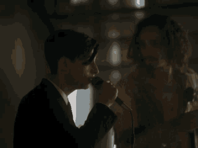 two men singing into microphones in the dark