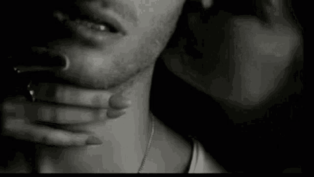 a black and white photo of a woman kissing a man on the neck .