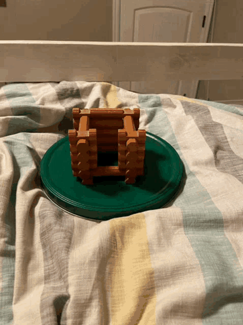 a toy log cabin is sitting on a green plate