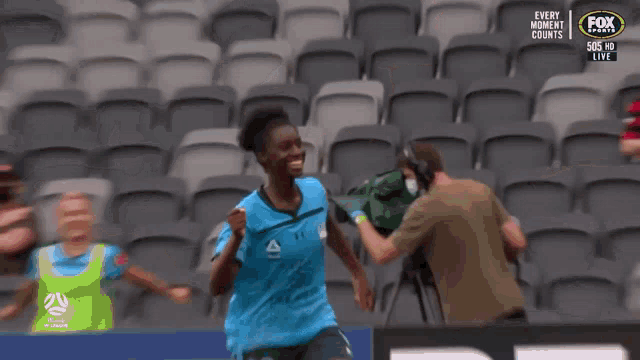 a soccer player wearing a blue under armour jersey is smiling in the stands .