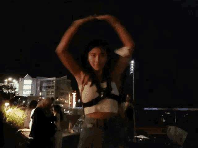 a woman in a crop top is dancing at night