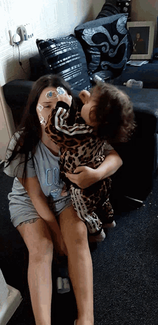 a little girl wearing a shirt that says cool is holding a baby