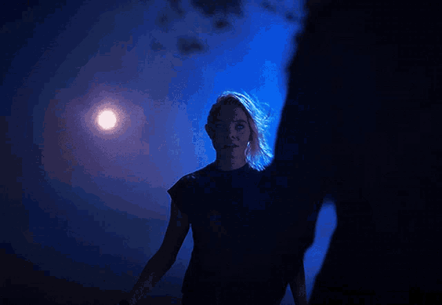 a woman in a black shirt is standing in the dark