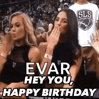 two women are sitting in the stands at a basketball game and one is blowing a kiss .