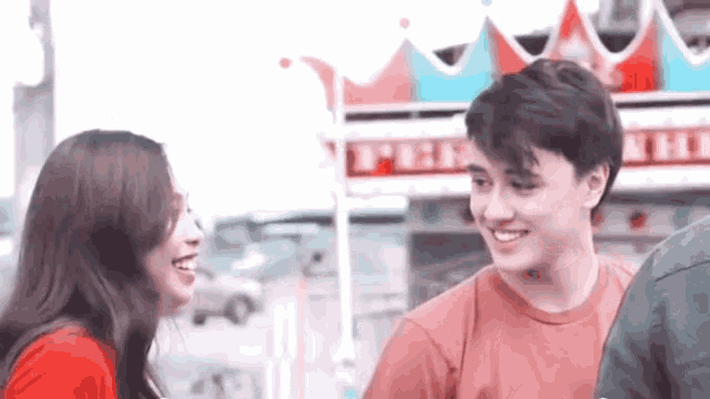 a boy and a girl are standing next to each other and smiling in front of a pizza hut .