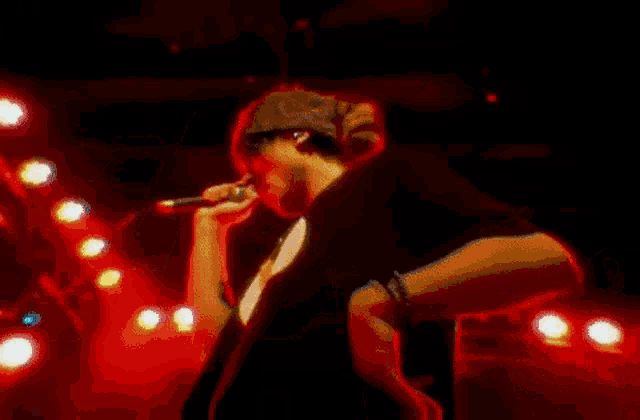 a man singing into a microphone in a dark room with red lights