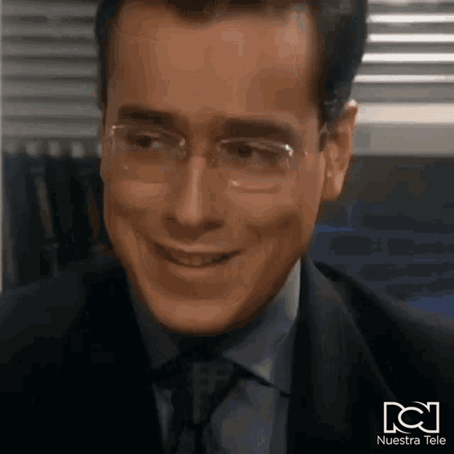a man wearing glasses and a suit is smiling for the camera