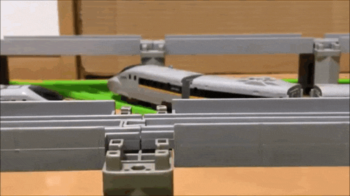 a toy train is going over a bridge in a toy train set .