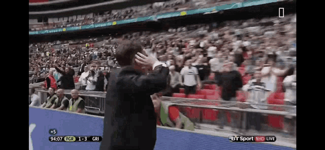 a man stands in front of a crowd at a soccer game on bt sport