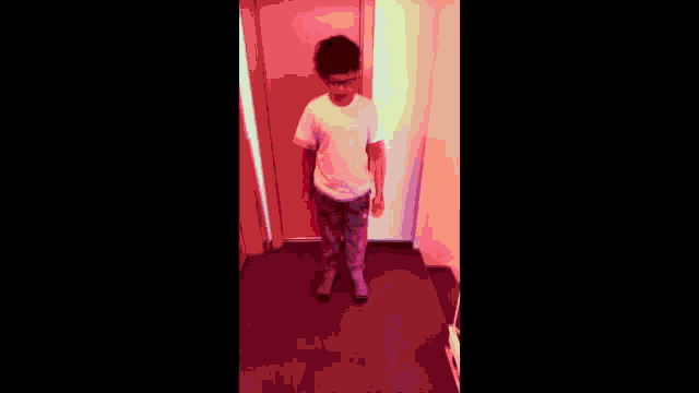 a young boy is standing in front of a pink door