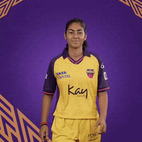 a woman is wearing a yellow and purple shirt that says kay beauty