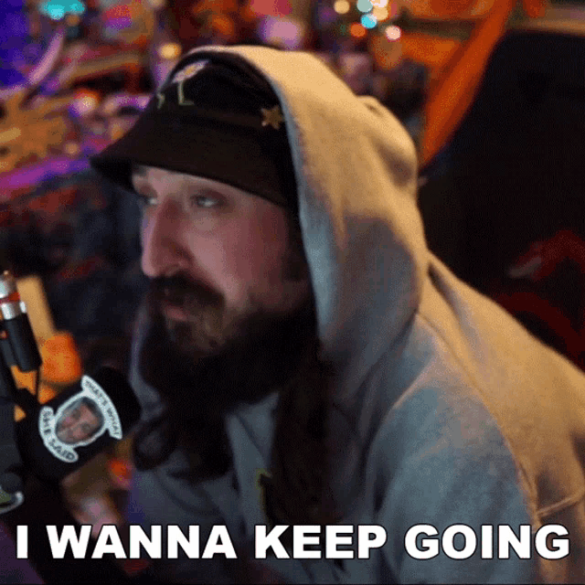 a man with long hair and a beard says i wanna keep going in front of a microphone