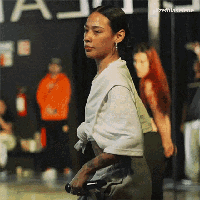 a woman in a white shirt stands in front of a sign that says ' lizethlaselene '