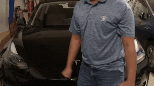 a man standing in front of a black tesla model 3