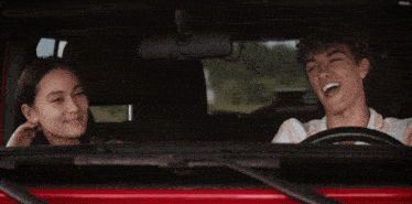 a boy and a girl are sitting in a car and smiling