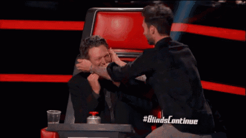 two men are sitting next to each other in a chair and one of them is holding the other 's face .