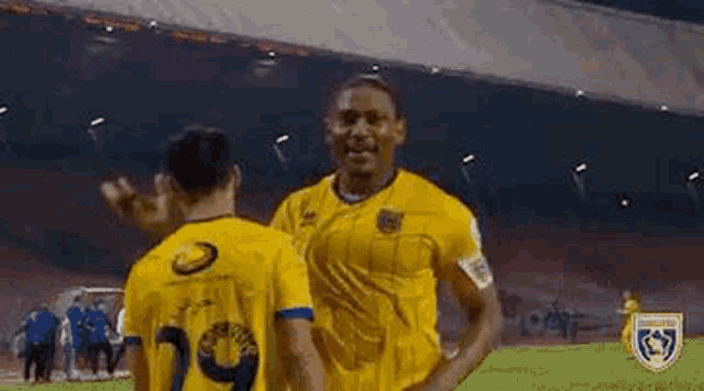 two soccer players are high fiving each other on a field .