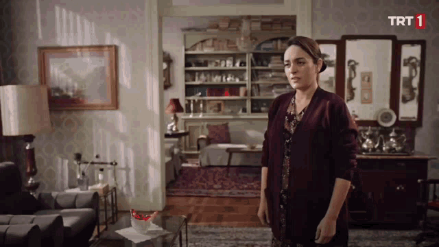 a woman in a living room with a trt 1 logo