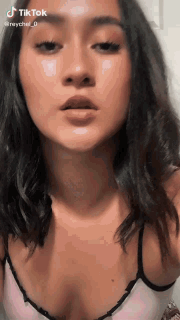 a woman in a pink bra is making a funny face and has tiktok written on her face