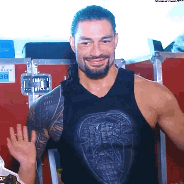 roman reigns is smiling and waving while wearing a black shirt