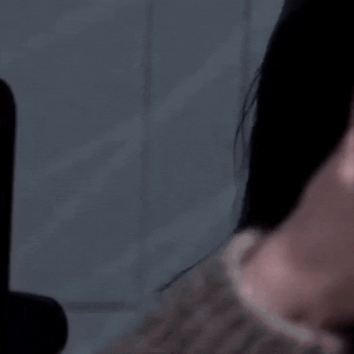 a close up of a woman covering her mouth with her hand while looking at a cell phone .