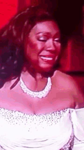 a woman in a white dress and pearl necklace smiles