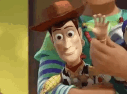 woody from toy story is holding buzz lightyear in his arms and waving his hand .