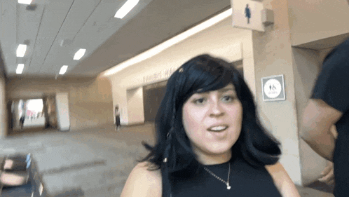 a woman stands in front of a sign that says " women 's restroom "