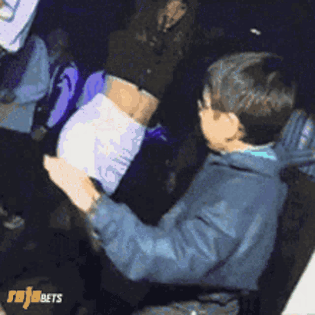 a man is dancing in a crowd with rojabets written on the bottom right