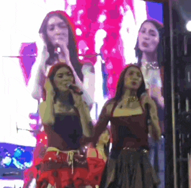 two women singing into microphones in front of a screen