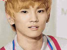 a close up of a young man 's face wearing a white shirt and suspenders