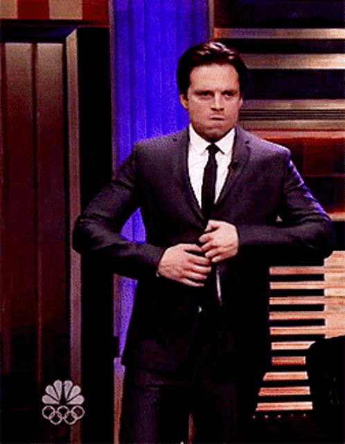 a man in a suit and tie is dancing in front of a nbc sign
