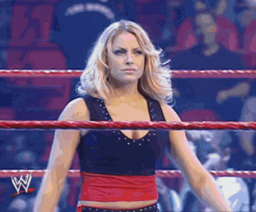 a woman is standing in a wrestling ring with a w logo on the side