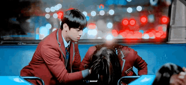 a man in a red suit is petting a woman 's hair while sitting on a bus .
