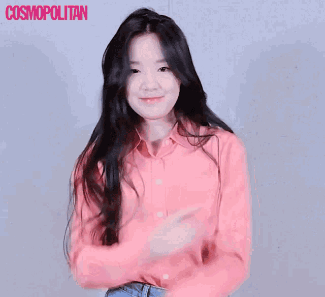 a woman in a pink shirt is dancing in front of a cosmopolitan banner