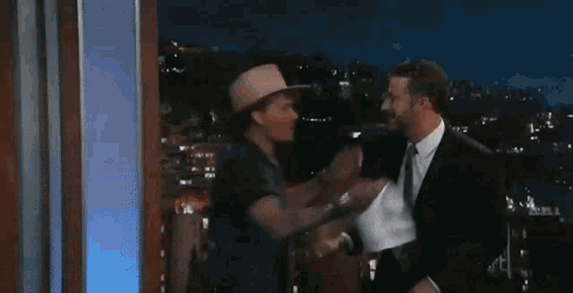 a man in a cowboy hat is touching another man 's face