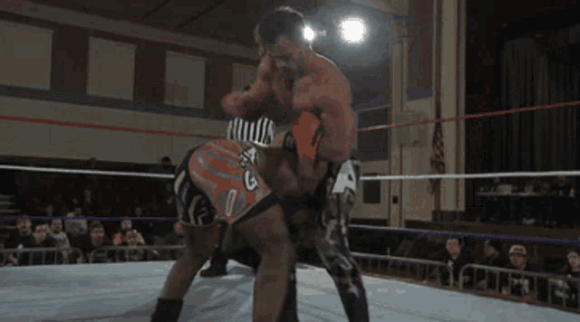 a wrestler with the number 5 on his shorts is wrestling another wrestler in a ring