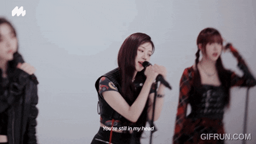 a woman singing into a microphone with the words " you 're still in my head " below her