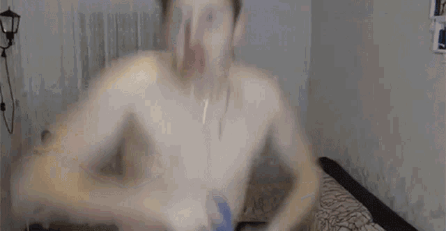 a shirtless man is standing in a living room holding a blue shirt .
