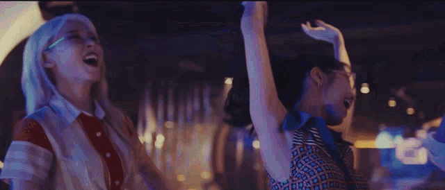 a group of women are dancing in a dark room with their arms in the air .
