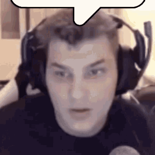 a man wearing headphones is making a funny face while sitting in front of a computer .